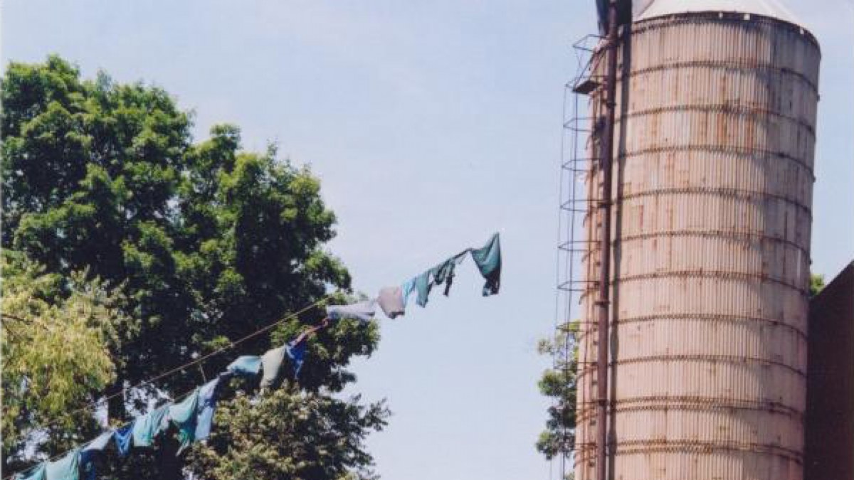 Clothes hanging to dry on a line connected to silo with an Amish buggy