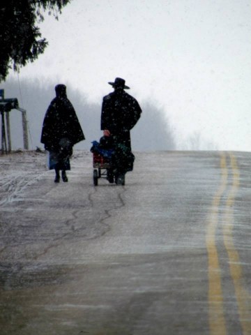 Amish couple pulling hand cart